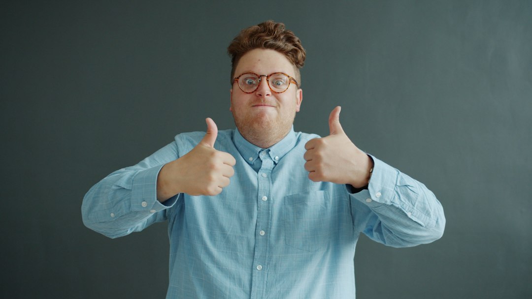 Man with glasses gives two thumbs up